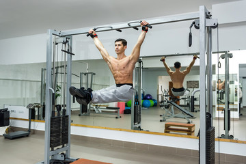 Young and athletic man doing exercises on crossbar