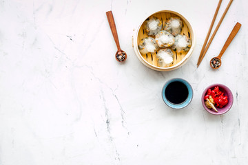 Dim sums with red pepper and vegetables with sticks and black tea in Chinese restaurant on marble background top view mockup