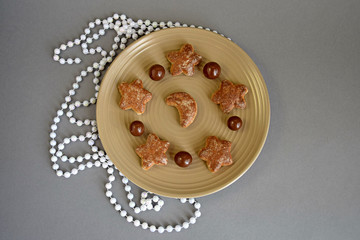 Confectionery, chocolate balls and cookies in a ceramic plate closeup. Chocolate candies, sweet cookies star and moon. Decor on new year. Top view.