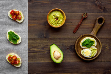 Healthy snacks. Set of toasts with vegetables like avocado, guacamole, rocket, cherry tomatoes on dark wooden background top view pattern
