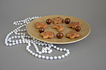  Confectionery, chocolate balls and cookies in a ceramic plate closeup. Chocolate candies, sweet cookies star and moon. Decor on new year.