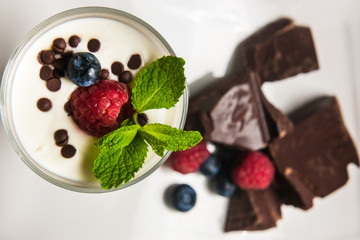 Yogurt with cream, chocolate, strawberry and muesli served in glass on the table