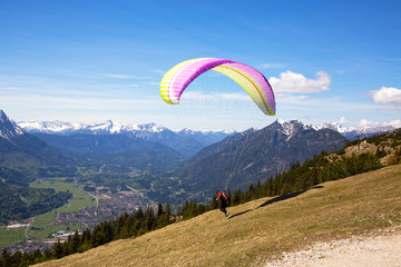 Paraglider setting off  from the Wank mountain for a flight above the valley of Garmisch-Partenkirchen, Germany. .