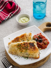 Fried fish with tomato-olive sauce and potatoes.