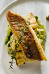 Fillet of halibut on a pillow of stewed leeks on the white plate.