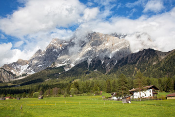 Fototapeta na wymiar View of the village of Ehrwald (Austria) and its beautiful surrounding mountains (Zugspitze Arena) and green alp meadows. Shot in afternoon sunlight.