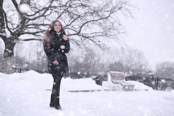 Fototapeta na wymiar Girl in a winter park in snowfall