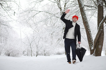 A man on a walk in the park. Young man with in the winter snowfall.