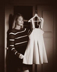 Young girl choose a dress at home near wardrobe in bedrood. interior in Dutch style . Image in sepia color style