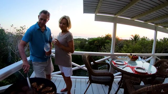Retired couple grilling meat outdoor at sunset Bahamas