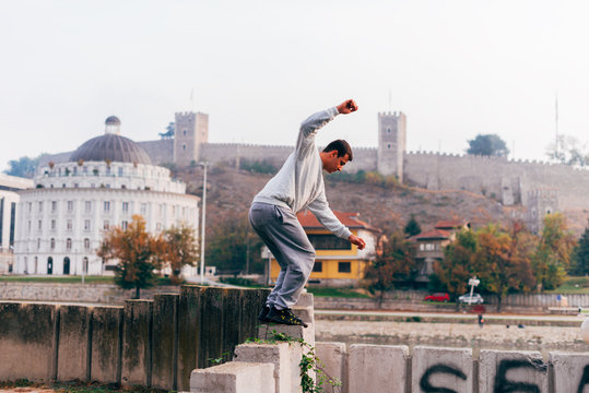 Free runner training parkour jumping on a fence while doing a back flip in the air.