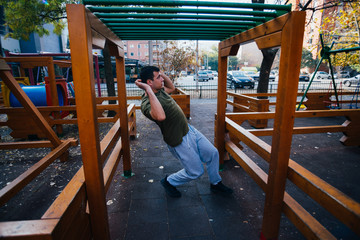 Young parkour guy doing tricks,flips and exercising at a playground.