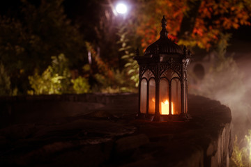 Fototapeta na wymiar Retro style lantern at night. Beautiful colorful illuminated lamp at the balcony in the garden. Selective focus