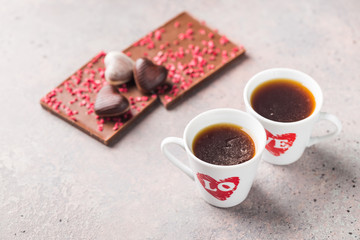 Two Cup of coffee with love and chocolate candies in a heart shape over gray background for Valentine's day conception