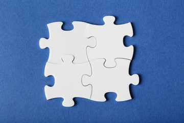 Four fastened puzzles of different colors on blue background