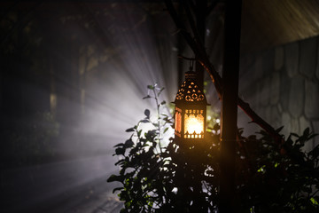Beautiful colorful illuminated lamp in the garden in misty night. Retro style lantern at night outdoor.