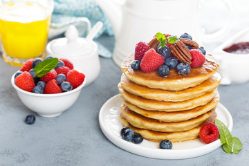 Stack of fluffy pancakes with fresh berries and pecan nuts