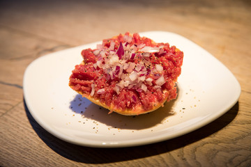 Teller Beef Tatar Mettbrötchen mit Rindfleisch und Zwiebeln auf Holz Tisch