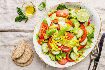 Healthy vegetable salad of fresh tomato, cucumber, lettuce and corn on plate, top view. Diet menu.