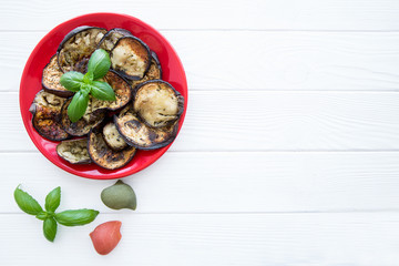 Grilled eggplants and basil leaves, space for text.