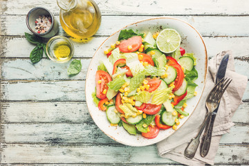 Healthy vegetable salad of fresh tomato, cucumber, lettuce and corn on plate, top view. Diet menu.