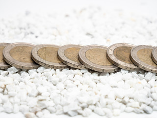 Image of line of two Euro coins on white little stones close up