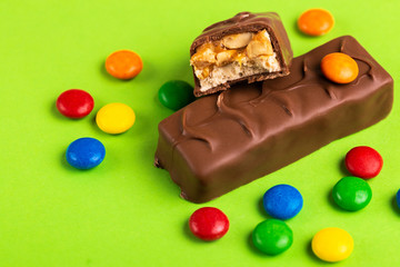 Tasty chocolate bars with toffee and colorful glazed round candies