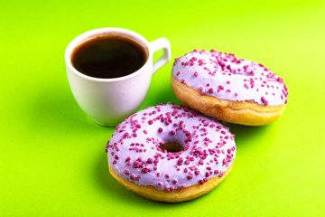 Two delicious lilac donuts with sprinkle and cup of coffee
