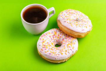 Two delicious vanilla donuts with sprinkle and cup of coffee