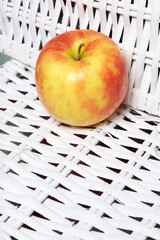 Juicy delicious apple. Lies on a white wicker basket.