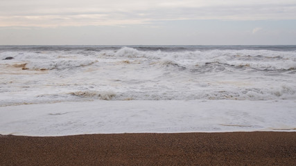 Stormy ocean sand beach, cloudy.