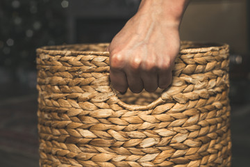 Obraz premium Hand holds old wicker basket in dark colors.