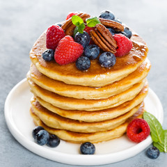 Stack of fluffy pancakes with fresh berries and pecan nuts