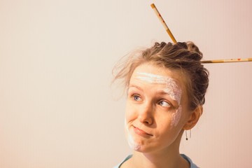 Girl with a soiled face flour and chopsticks in her hair on a white background. Girl with...