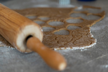 close up of a rolling pin and a biscuit dough with cutted out cookies