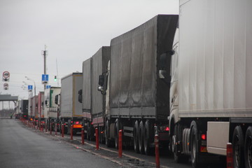 Truck inspection - a long congestion traffic of many trucks with semi trailers convoy on weight...