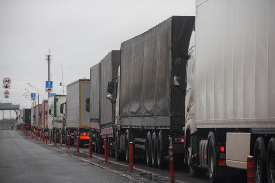 Truck inspection - a long congestion traffic of many trucks with semi trailers convoy on weight control point. Logistics, delivery, overload