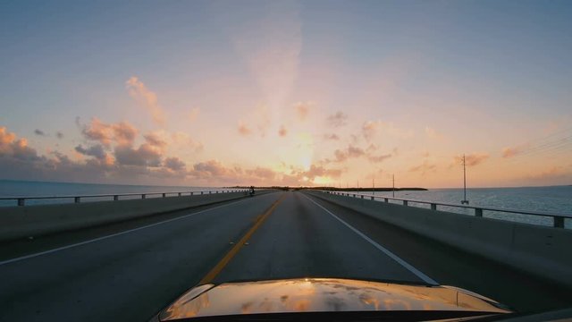 Driving a car along Florida Keys highway bridge through the sunset. POV