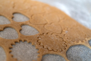 Fototapeta na wymiar close up of biscuit dough with cutted out cookies in heart shape for valentines day