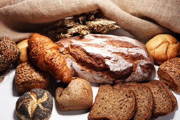 Different kinds of bread and bread rolls on board from above.