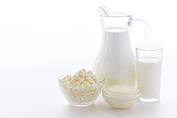  Fresh cow milk in a glass on a white background with a useful curd and sour cream. Dairy kitchen is very useful for bone health.