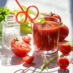 Tomato juice in glass with celery, cherry tomato, white wood background, closeup. Healthy eating concept.