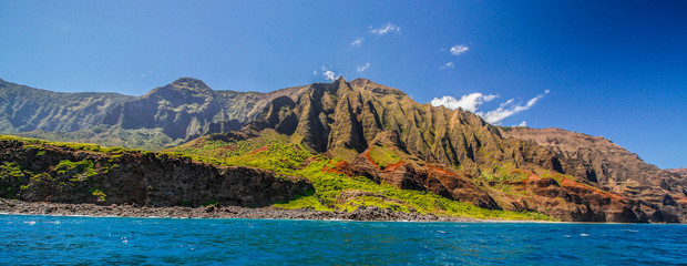 Fototapeta na wymiar Panoramic view taken from the sea of Na Pali Coast, island of Kauaii, Hawaii, showing spectaculr high cliffs above a blue sea