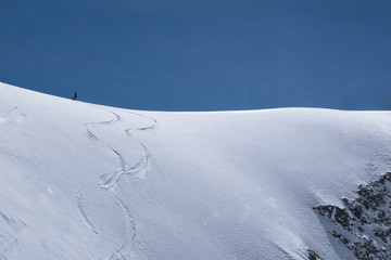 Single skier on top of snowridge waiting to drop in