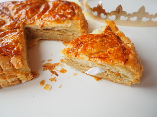 Homemade Epiphany cake or Twelfth Night cake (french galette des rois) made of puff pastry and frangipane (almond cream), white background