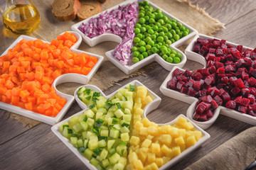 Raw vegetables carrots, peas, onions, cucumber, potatoes, beets cut into cubes lie on plates that are collected in puzzles.Healthy eating concept.