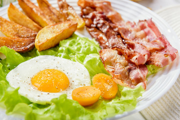 Egg with bacon. Fried bacon. Fried bacon with French fries and a delicate egg, close-up.