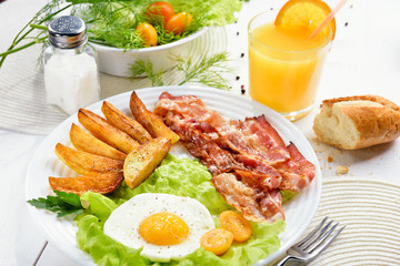 Roast potatoes. Morning breakfast with delicious fried bacon, French fries and tender egg, close-up. Roast potatoes.