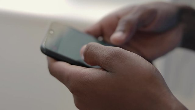Close up shot of african american student using smartphone. Male hands holding modern phone. Technology concept
