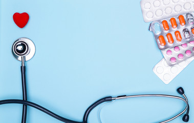 Closeup of a painted heart, a lot of drugs and a stethoscope on a blue background.Statoscope, heart, medicine on a blue background.concept of treating cardiovascular diseases.